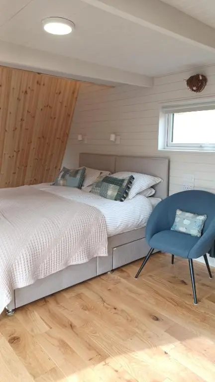 a bedroom with a bed and a blue chair at Little Getaway in the Highlands, private sauna and stargazing geodome in Garve