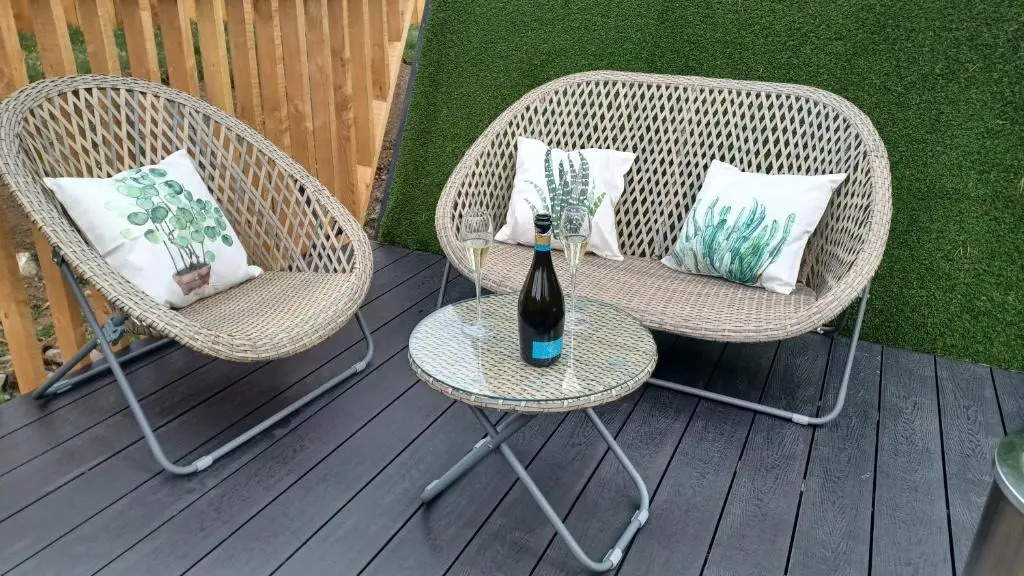 two wicker chairs and a bottle of wine on a table at Little Getaway in the Highlands, private sauna and stargazing geodome in Garve