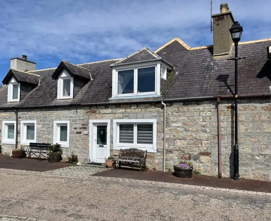 a stone house with white windows and a roof at Beach Croft, Brora in Brora