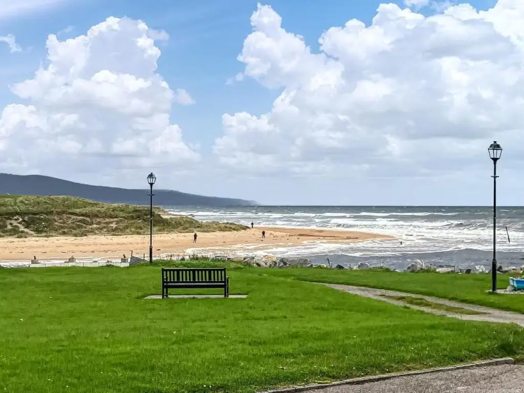 a park bench sitting on the grass near the beach at Beach Croft, Brora in Brora