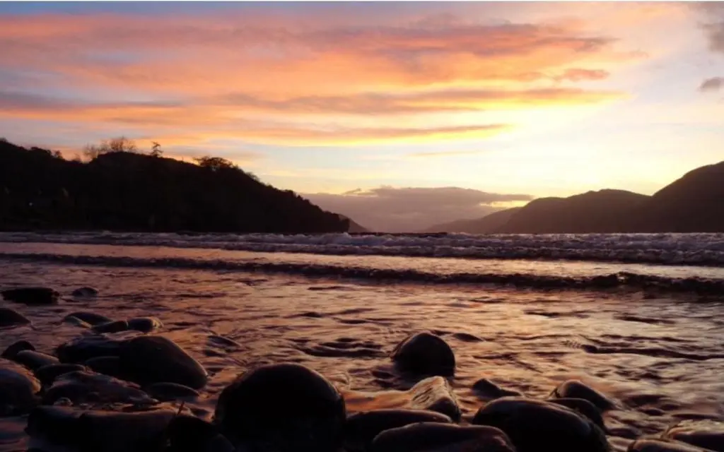 a group of rocks on the beach at sunset at The Loft at Log Ness in Inverness