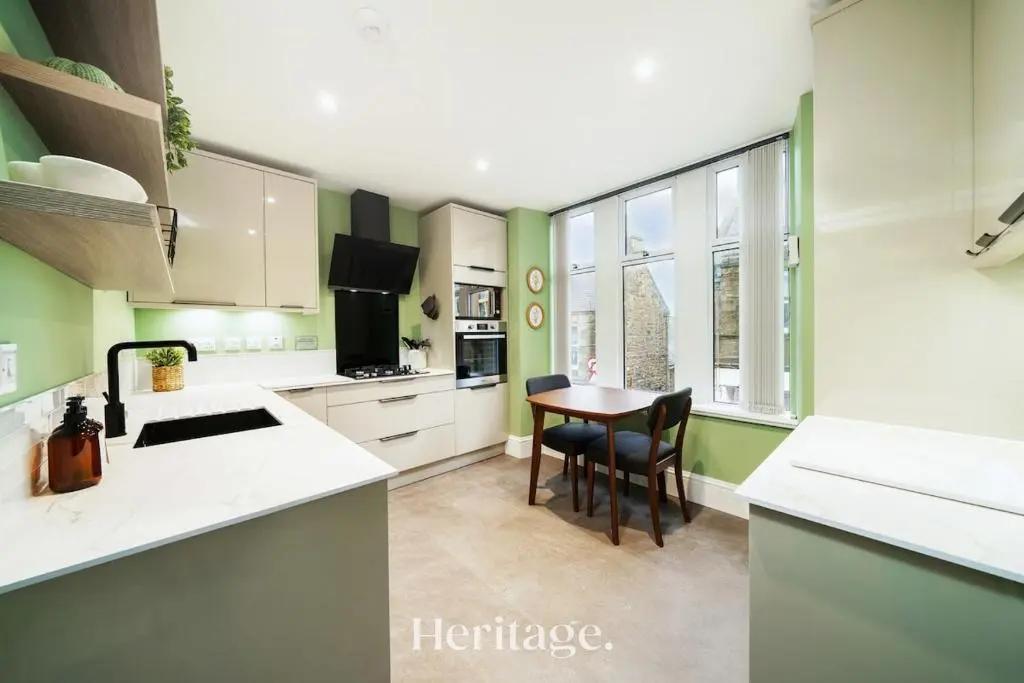a kitchen with green walls and a table and chairs at The Copper Loft Apartment, Keith in Keith