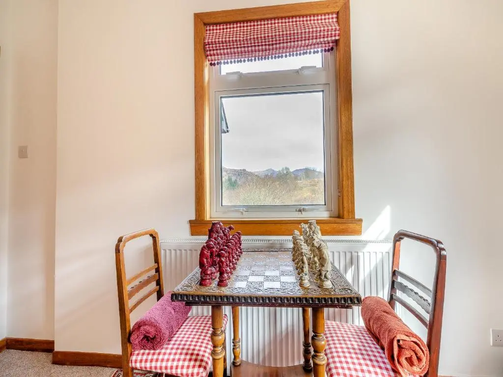 a table with two chairs and a window at Clunie Dam Lodge in Blair Atholl