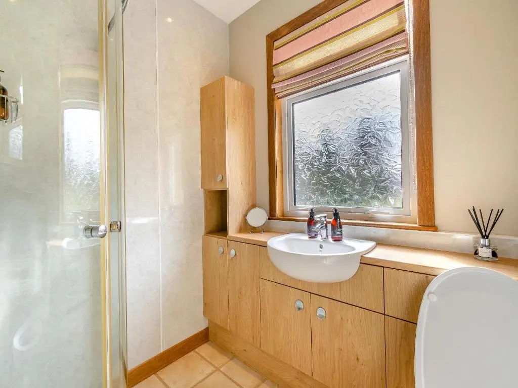 a bathroom with a sink and a window and a shower at Clunie Dam Lodge in Blair Atholl
