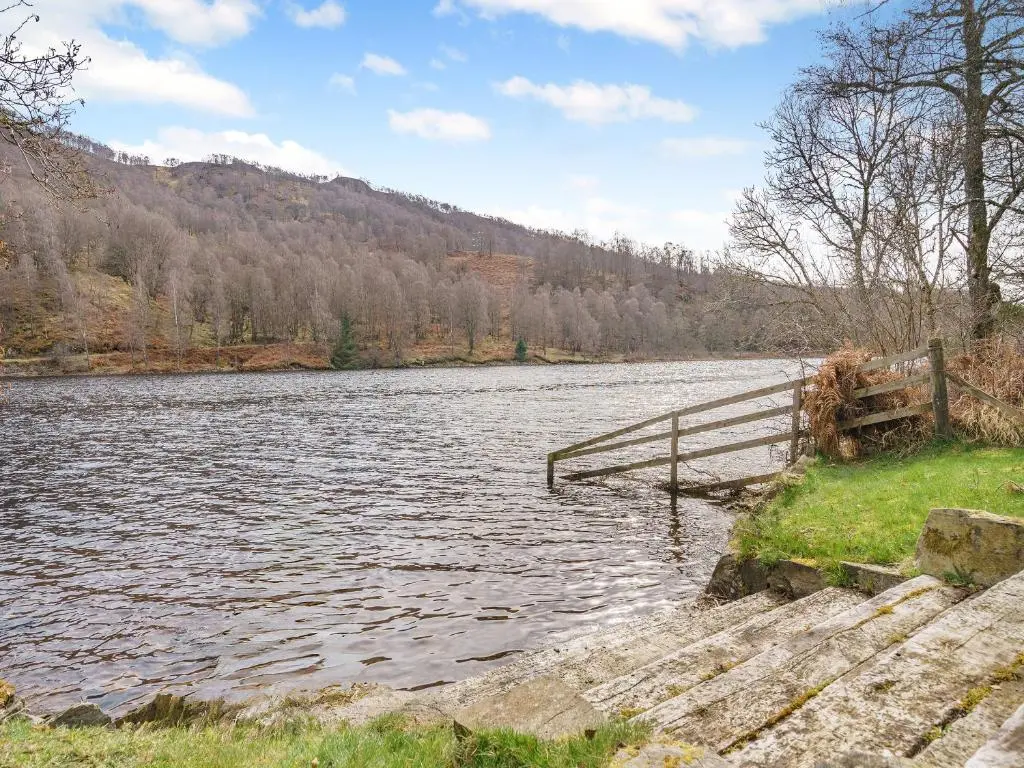a body of water with a wooden fence and stairs at Clunie Dam Lodge in Blair Atholl