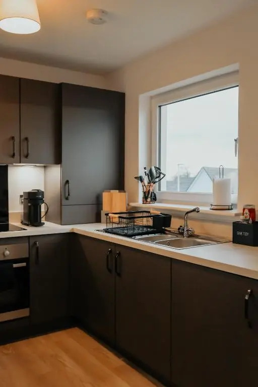 a kitchen with black cabinets and a sink and a window at Luxurious Apartment in Inverness in Inverness