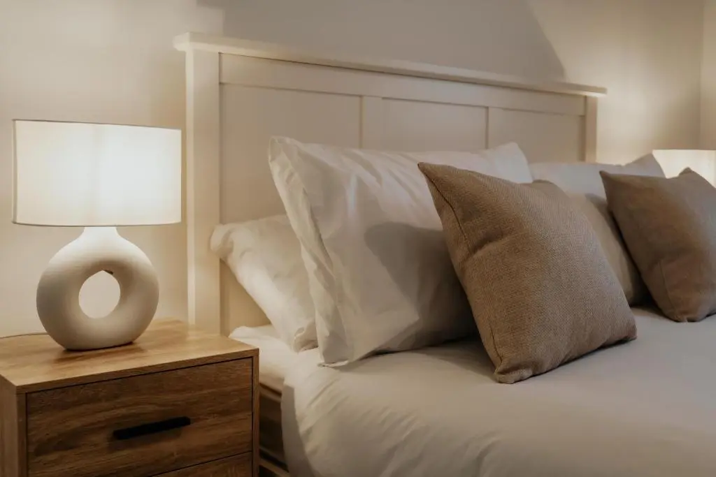 a bed with white pillows and a lamp on a night stand at Luxurious Apartment in Inverness in Inverness