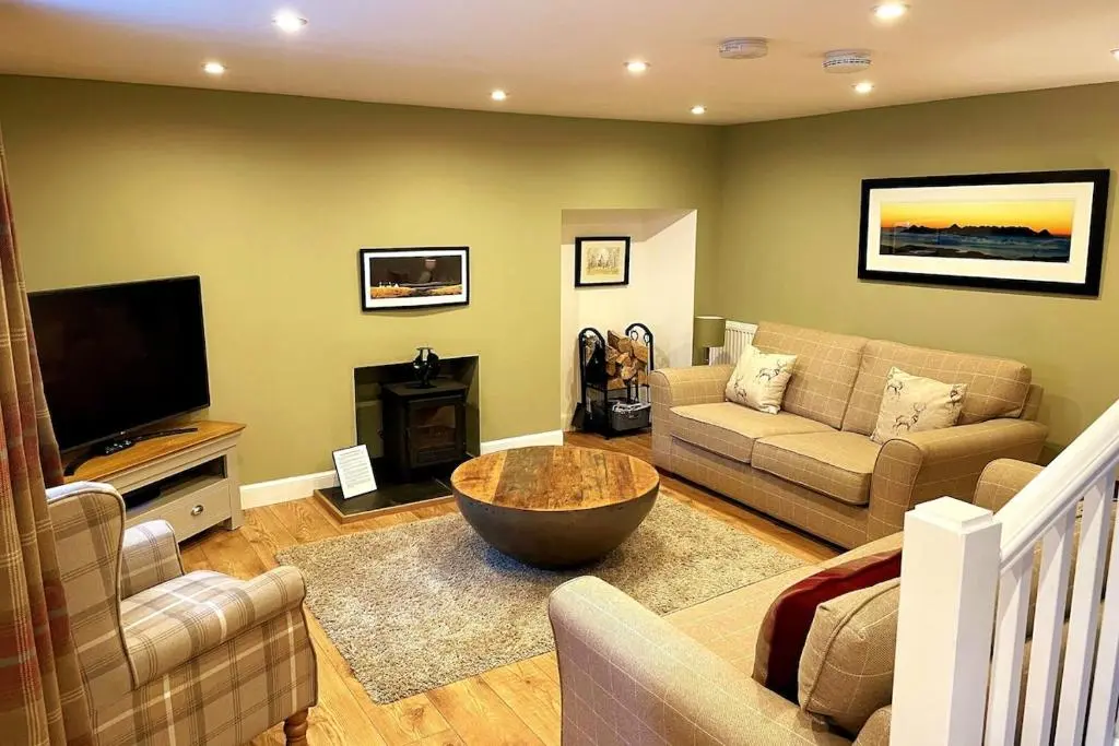 a living room with a couch and a tv at Cosy Carnegie Cottage close to Dornoch Golf Course in Dornoch