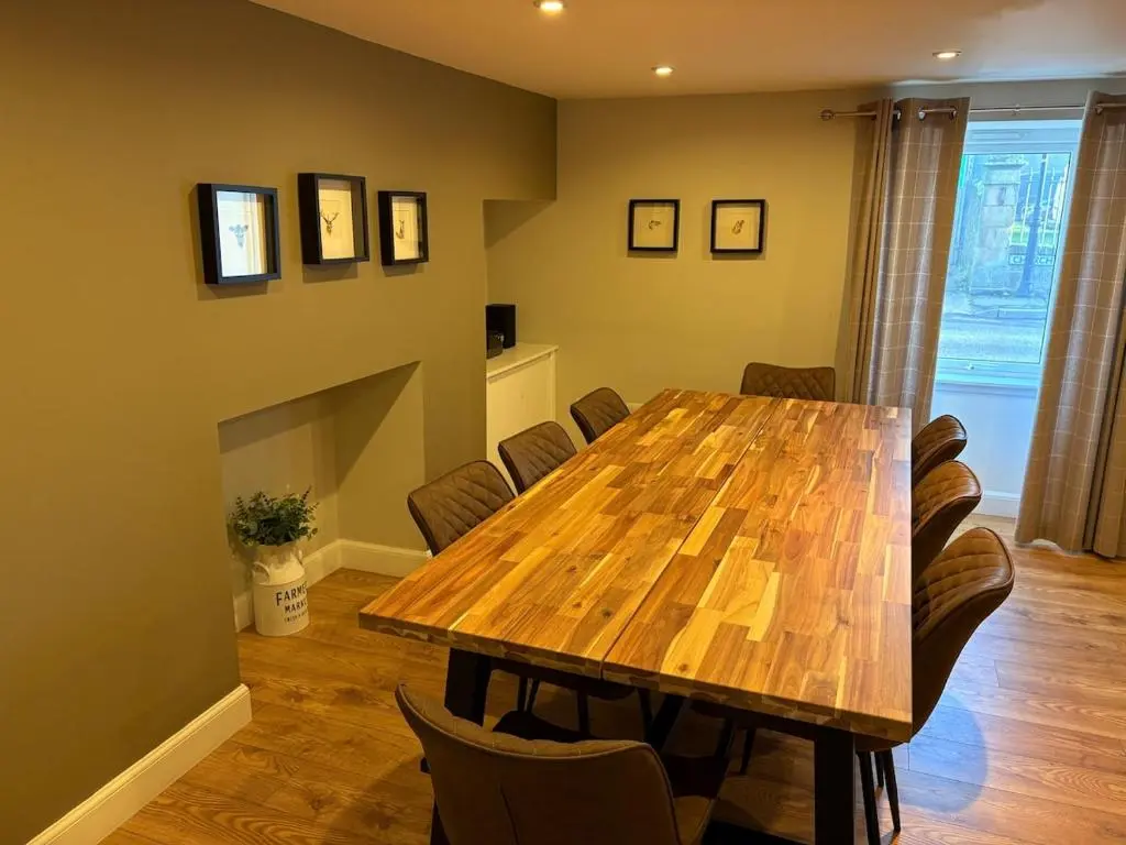 a dining room with a wooden table and chairs at Cosy Carnegie Cottage close to Dornoch Golf Course in Dornoch