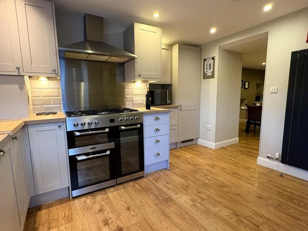 a kitchen with white cabinets and a stove top oven at Cosy Carnegie Cottage close to Dornoch Golf Course in Dornoch