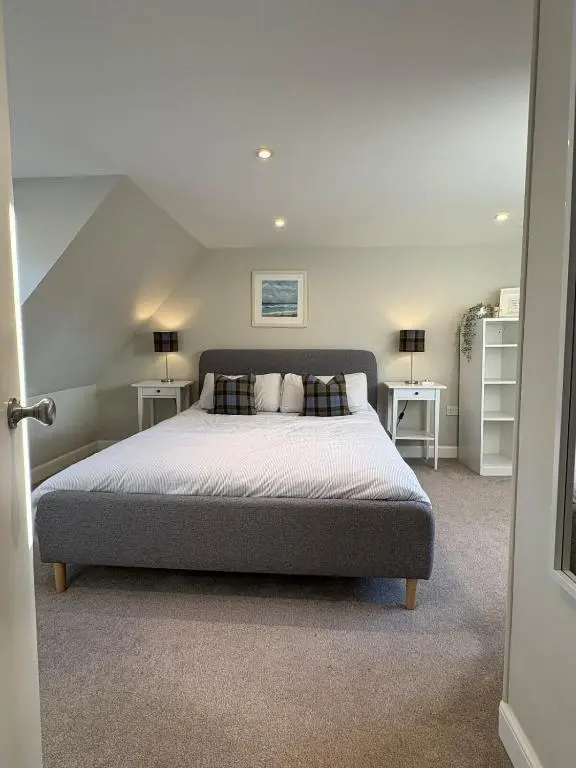 a bedroom with a bed and two tables and two lamps at Cosy Carnegie Cottage close to Dornoch Golf Course in Dornoch