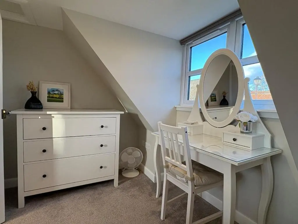 a bedroom with a dressing table and a mirror at Cosy Carnegie Cottage close to Dornoch Golf Course in Dornoch