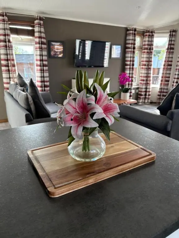 a vase filled with pink flowers on a wooden tray at Hepburns Lodge 19 in Strachan