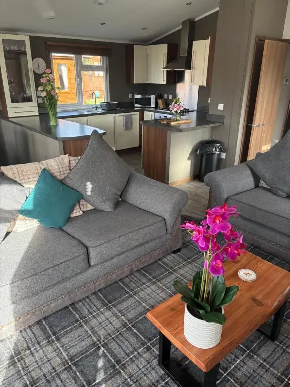 a living room with a couch and a table with flowers at Hepburns Lodge 19 in Strachan