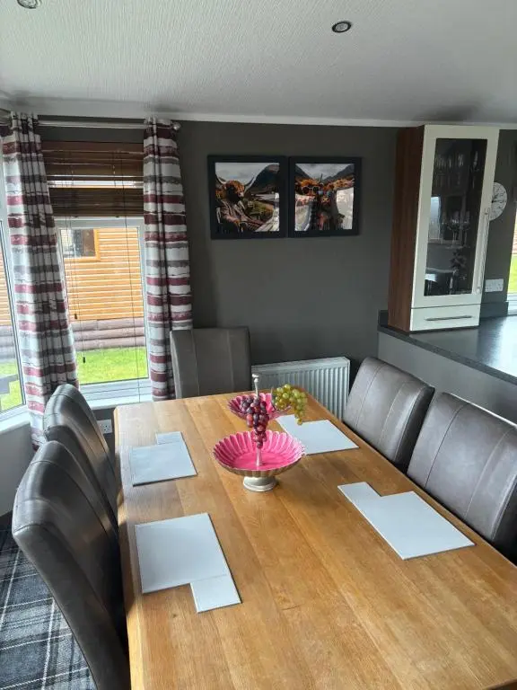 a dining room with a wooden table and leather chairs at Hepburns Lodge 19 in Strachan
