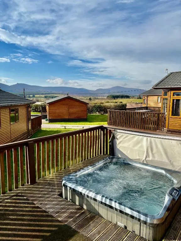 a hot tub on the deck of a house at Hepburns Lodge 19 in Strachan