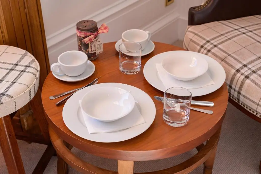 a wooden table with plates and glasses on it at Netherley Rooms in Ballater