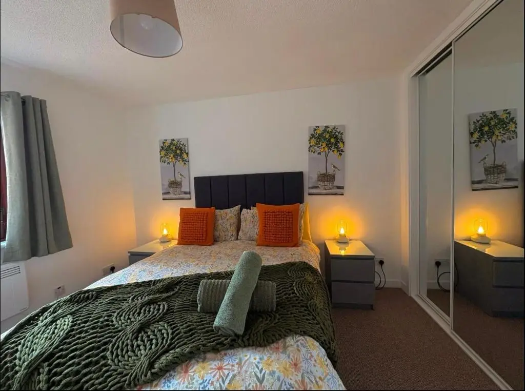 a bedroom with a bed with orange pillows and two lamps at Elegant Apartment In City Centre in Inverness