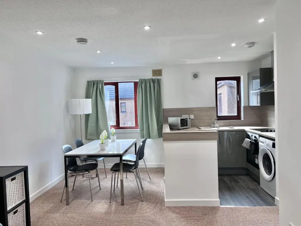 a kitchen and dining room with a table and chairs at Elegant Apartment In City Centre in Inverness