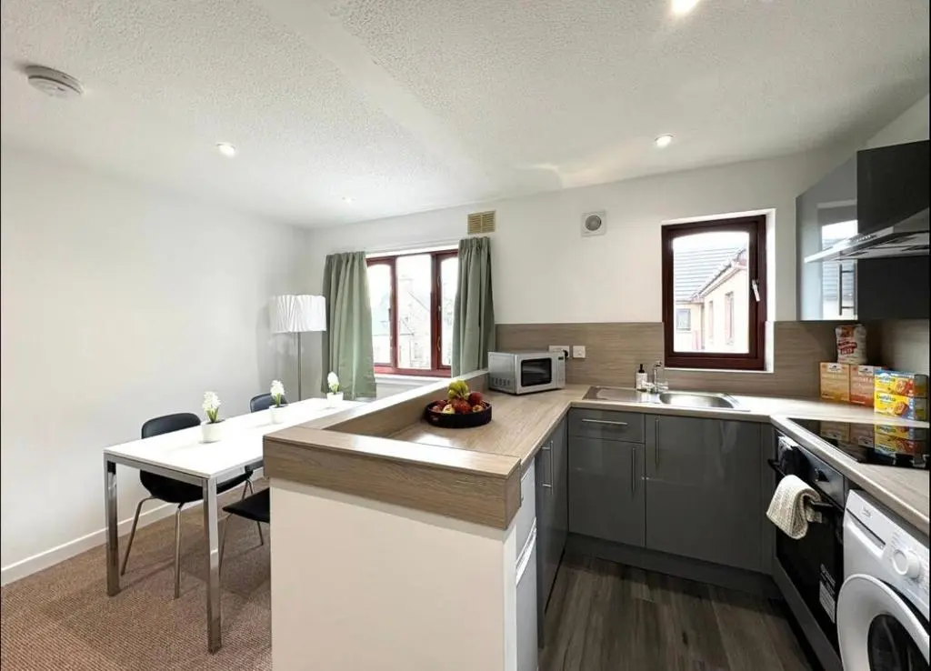 a kitchen with a sink and a table in it at Elegant Apartment In City Centre in Inverness