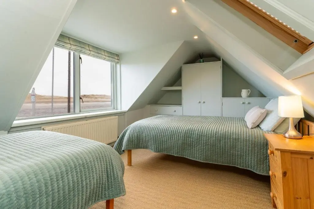 a attic bedroom with two beds and a window at Fishermans Cottage in Lossiemouth