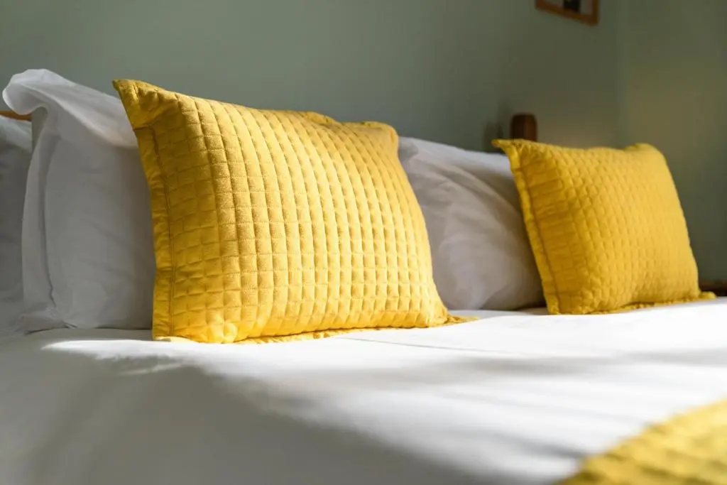 a bed with yellow pillows and white sheets at Pinewood 3 Bedroom House in Inverness with Views in Inverness