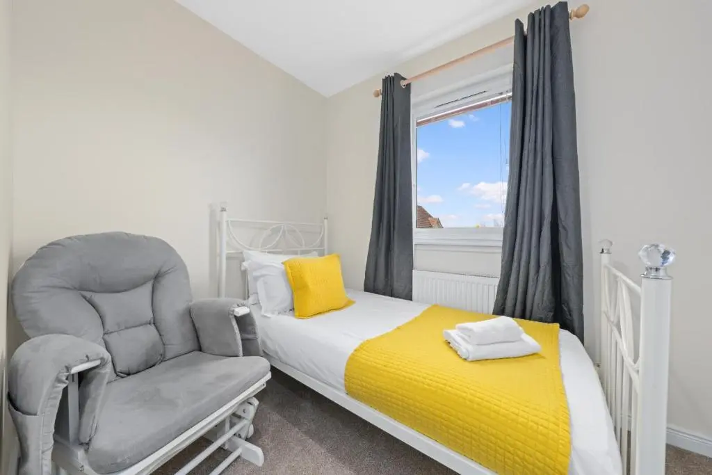 a bedroom with a bed and a chair and a window at Pinewood 3 Bedroom House in Inverness with Views in Inverness