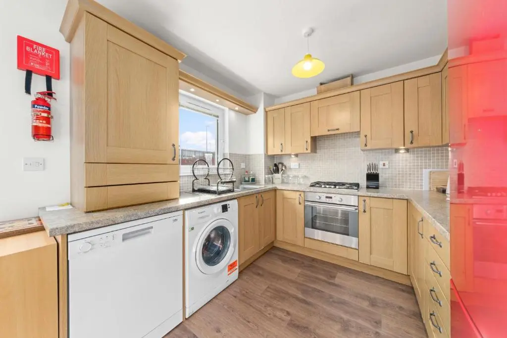 a kitchen with wooden cabinets and a washer and dryer at Pinewood 3 Bedroom House in Inverness with Views in Inverness