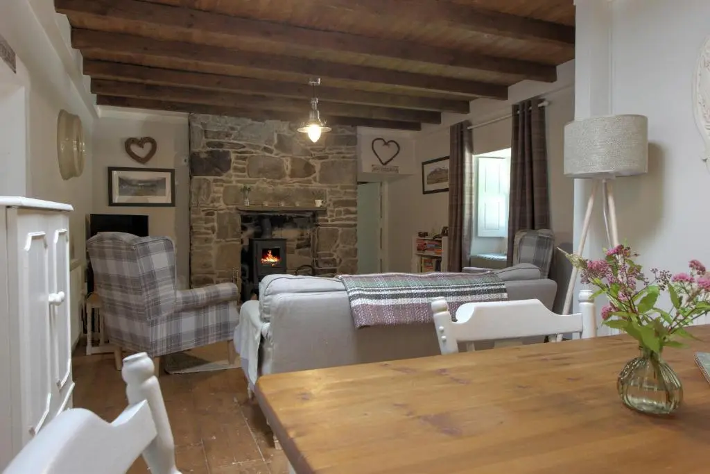a living room with a couch and chairs and a fireplace at Bridge Cottage in Glenlivet