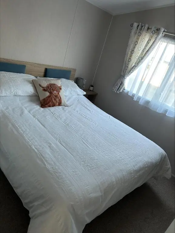 a white bed with a teddy bear sitting on it at Silversands holiday park new caravan in Lossiemouth