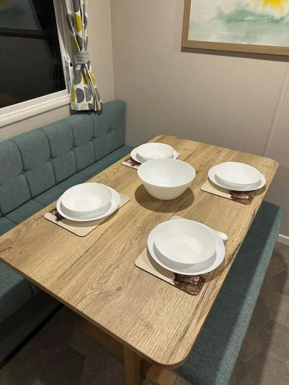 a wooden table with white plates and bowls on it at Silver Dunes in Lossiemouth