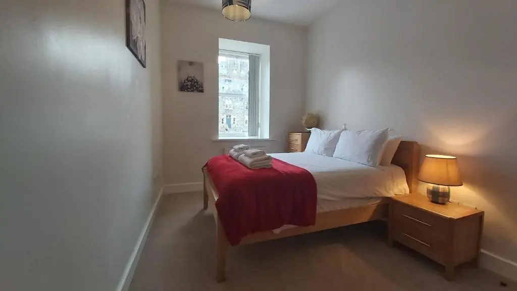 a bedroom with a bed with a red blanket on it at Moat House - Highland Club in Fort Augustus