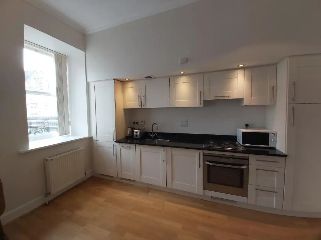 an empty kitchen with white cabinets and a microwave at Moat House - Highland Club in Fort Augustus