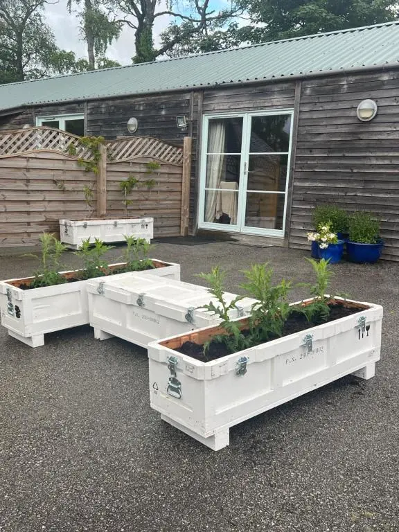 three white planters with plants in them in front of a house at The Space at the Creamery - Royal Deeside in Torphins