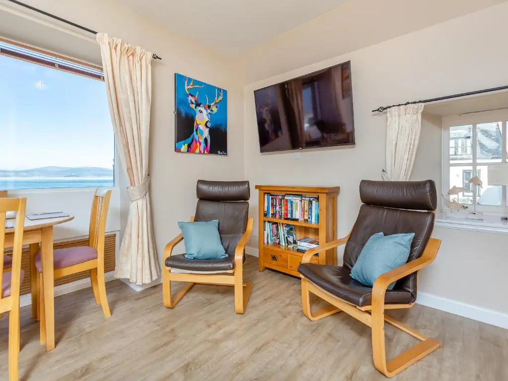 a living room with a table and chairs and a television at Harbour View in Cromarty
