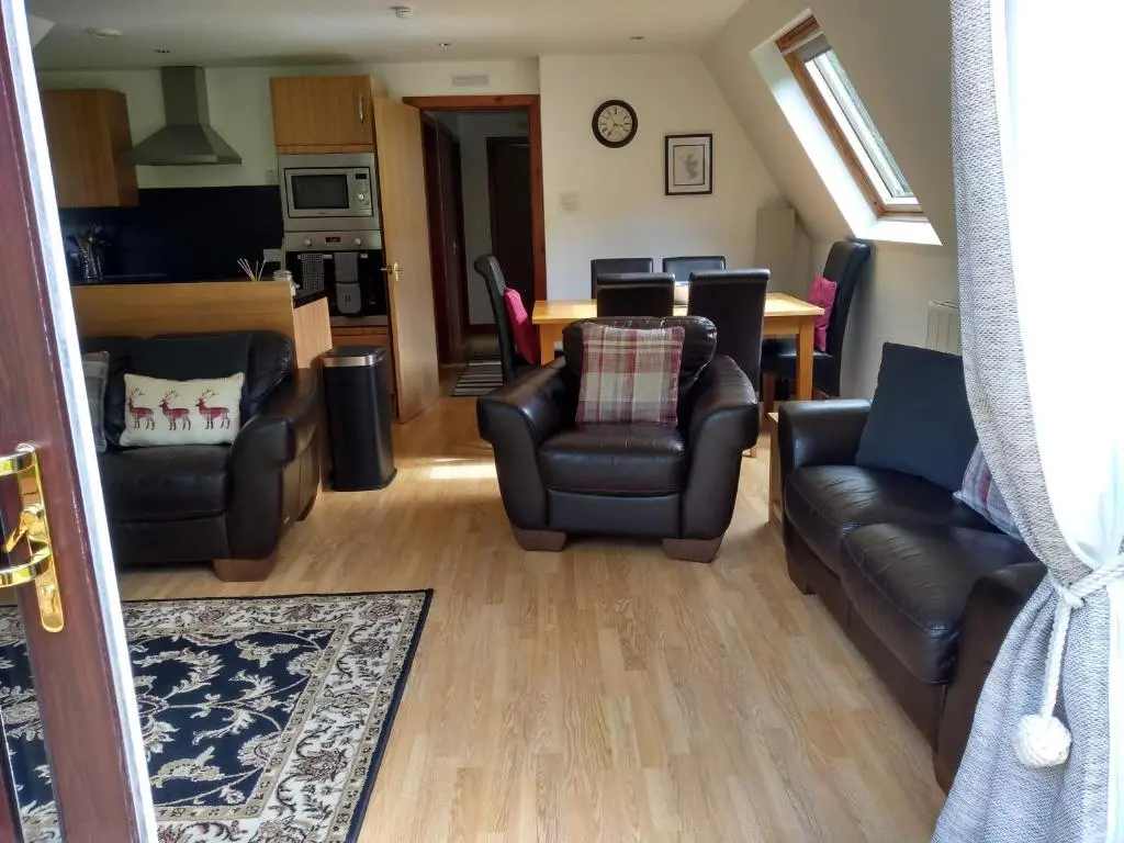 a living room with two leather couches and a table at True North Lodge - A cosy wee highland Getaway in Spean Bridge