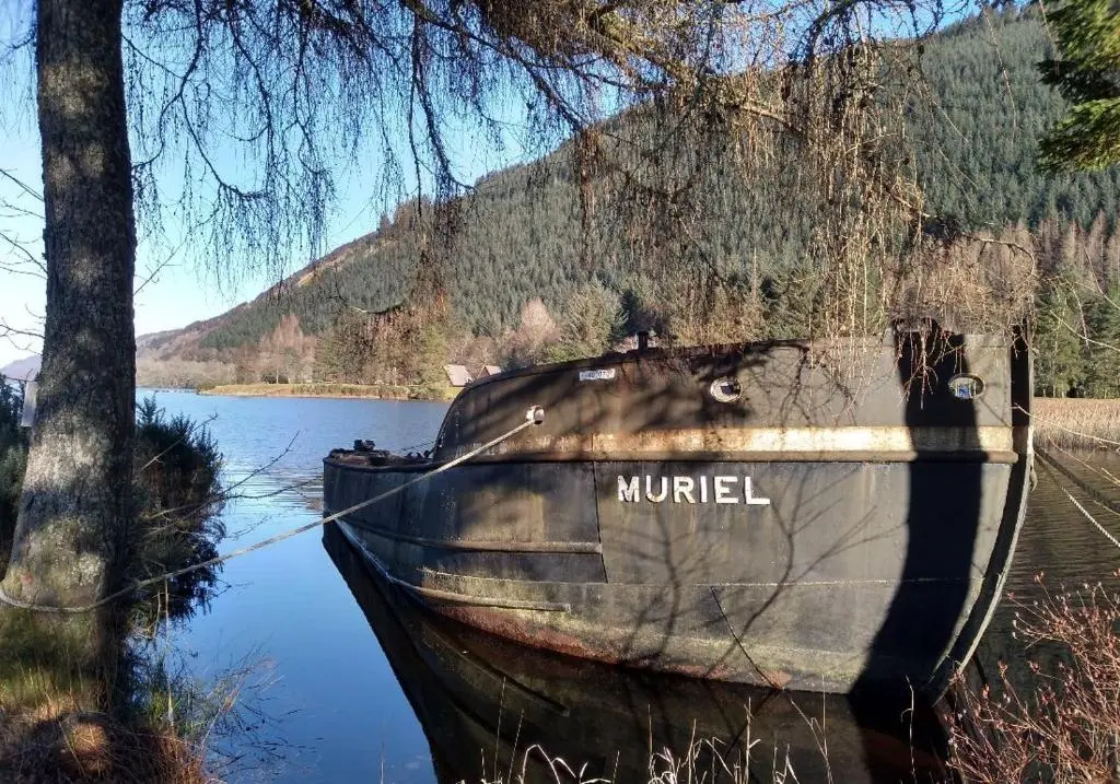 a boat sitting on the side of a lake at True North Lodge - A cosy wee highland Getaway in Spean Bridge