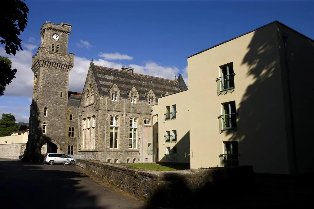 a building with a clock tower and a car parked in front at Highland Club Scotland Apartments in Fort Augustus