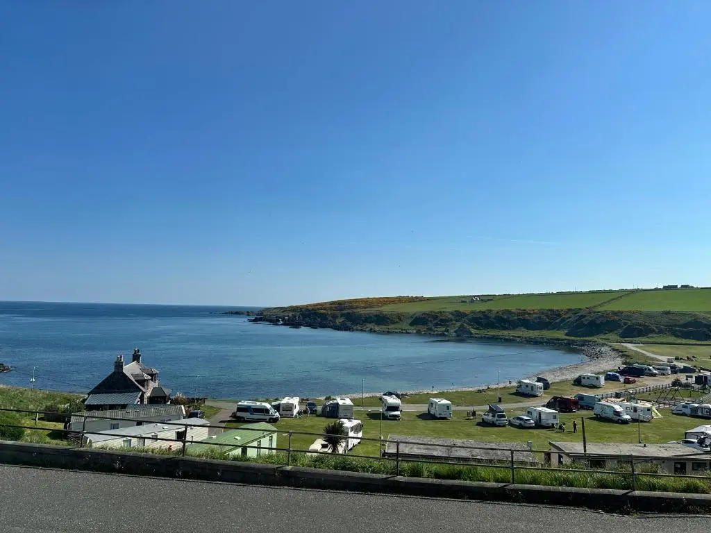 a group of cars parked in a field next to a body of water at Cozy Cottage Retreat in Portsoy