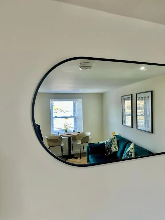 a mirror reflecting a living room with a couch and a table at Cozy Cottage Retreat in Portsoy