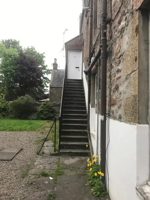 a stairway leading up to a white door with a backdoor at Butterfly Apartment in Inverness