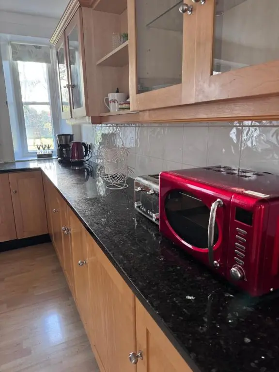 a red microwave sitting on top of a kitchen counter at 19th century 5-bedroom villa with free private parking in Elgin