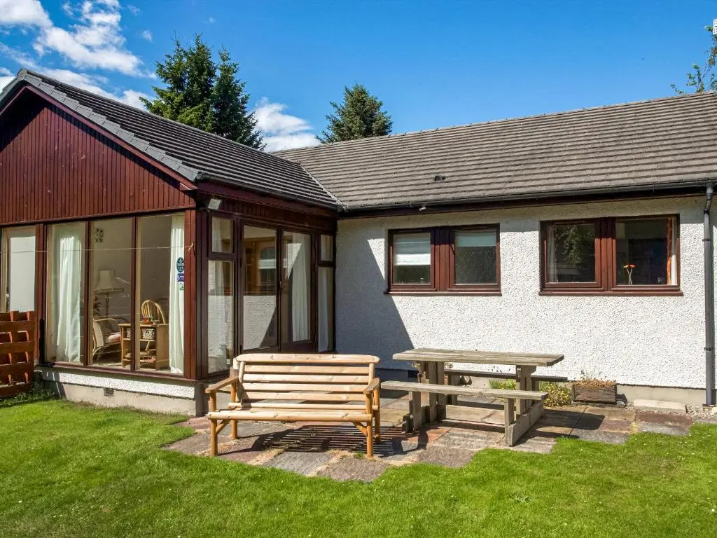 a picnic table and a bench in front of a house at Heath Cottage in Boat of Garten