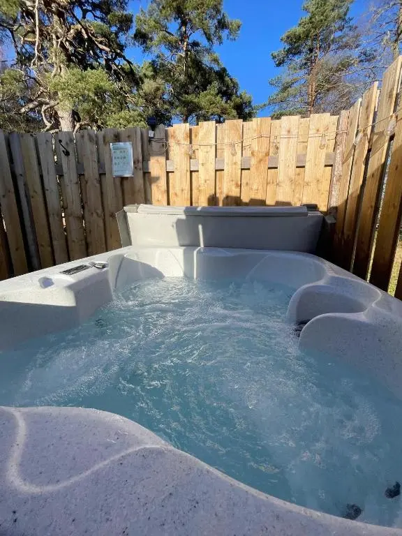 a hot tub in a backyard with a wooden fence at Kaoglen - Alpine Pod - Hot Tub - Cairngorms - Pitlochry in Kirkmichael