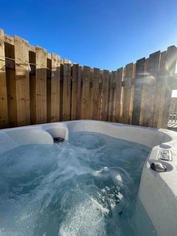 a hot tub in a backyard with a wooden fence at Kaoglen - Alpine Pod - Hot Tub - Cairngorms - Pitlochry in Kirkmichael