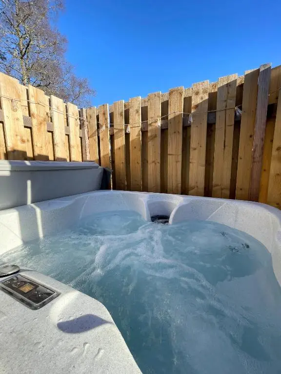 a hot tub in front of a wooden fence at Kaoglen - Alpine Pod - Hot Tub - Cairngorms - Pitlochry in Kirkmichael