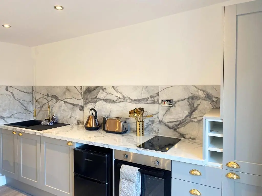 a kitchen with a marble counter top and blue cabinets at Kaoglen - Bali Pod - Hot Tub -Cairngorms - Pitlochry in Kirkmichael