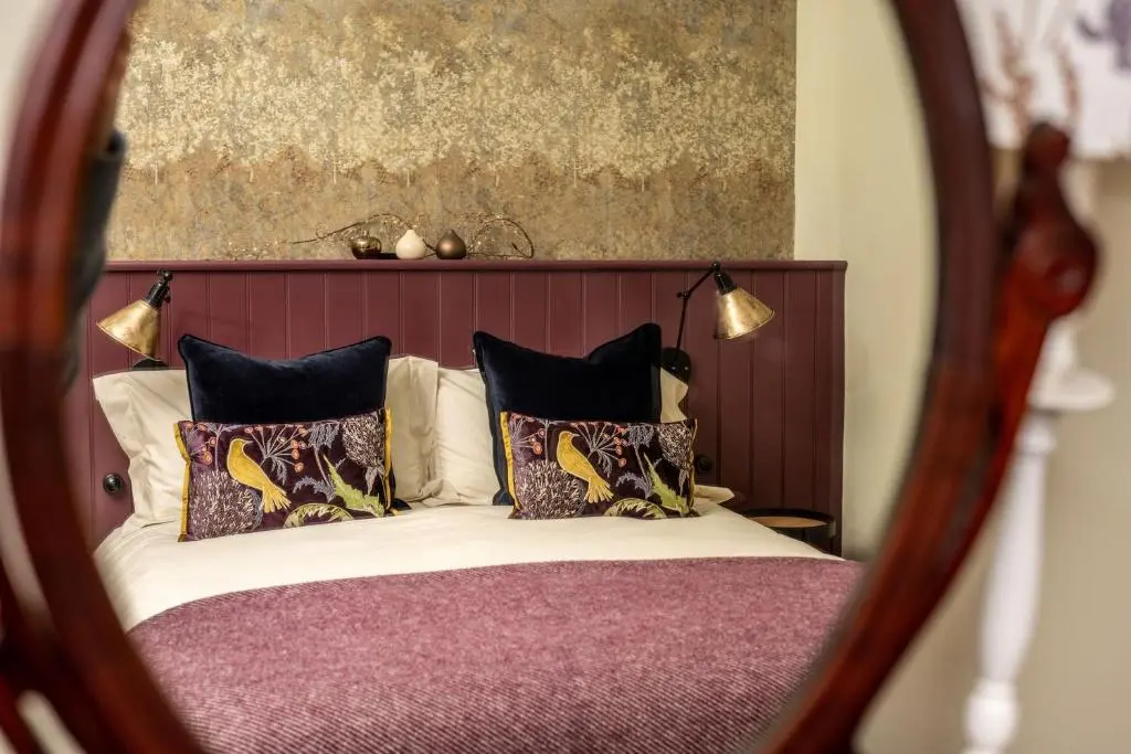 a mirror reflecting a bed with pillows on it at Old Duffus Farmhouse in Duffus