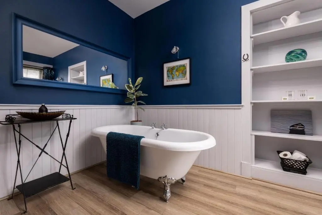 a bathroom with a white tub and a blue wall at Old Duffus Farmhouse in Duffus