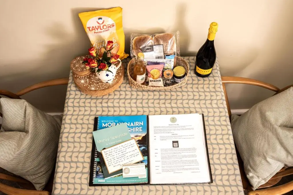 a table with a bottle of wine and a book at Duffus House Lodge in Duffus